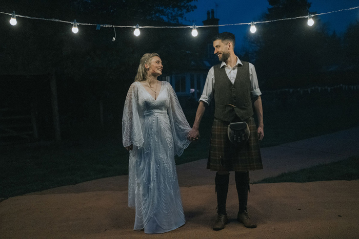 Night time couple portrait with fairy lights illuminating pair 