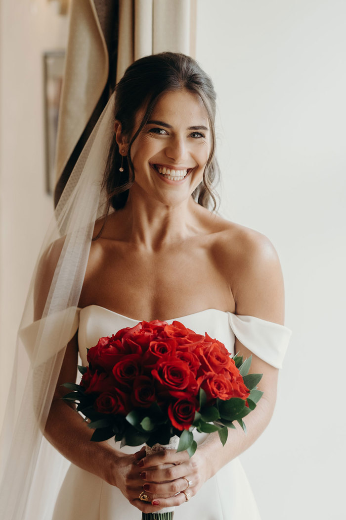  A bride in a white dress and veil holding a bouquet of red roses