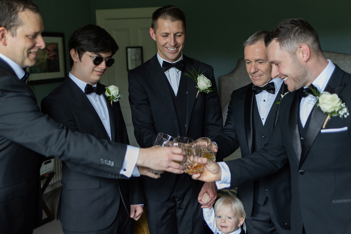 Groom and groomsmen cheers their glasses