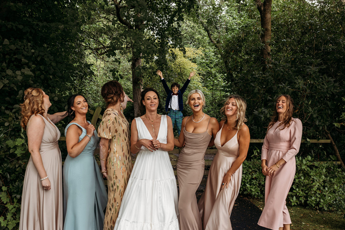 People Posing For A Wedding Group Portrait With A Boy In Tartan Trousers Photobombing In Background