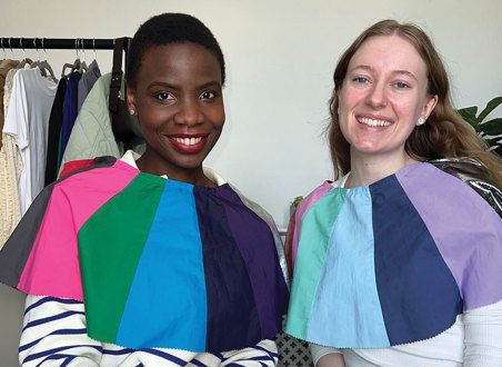 two women sit side by side with differently coloured fabric draped across their shoulders for comparison 