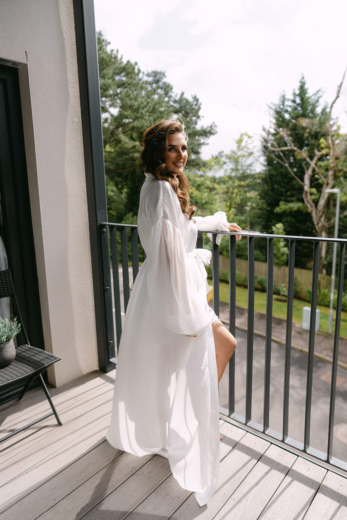 A woman in a long translucent white robe leaning on a railing