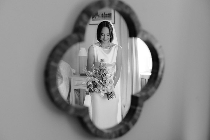 a reflection of a bride in a shaped mirror