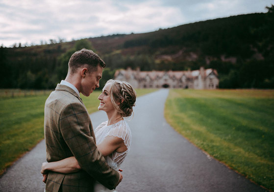 bride and groom look at one another with mar lodge in background