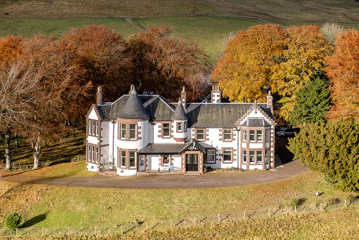 a large white and brown stately home surrounded by colourful autumn foliage 