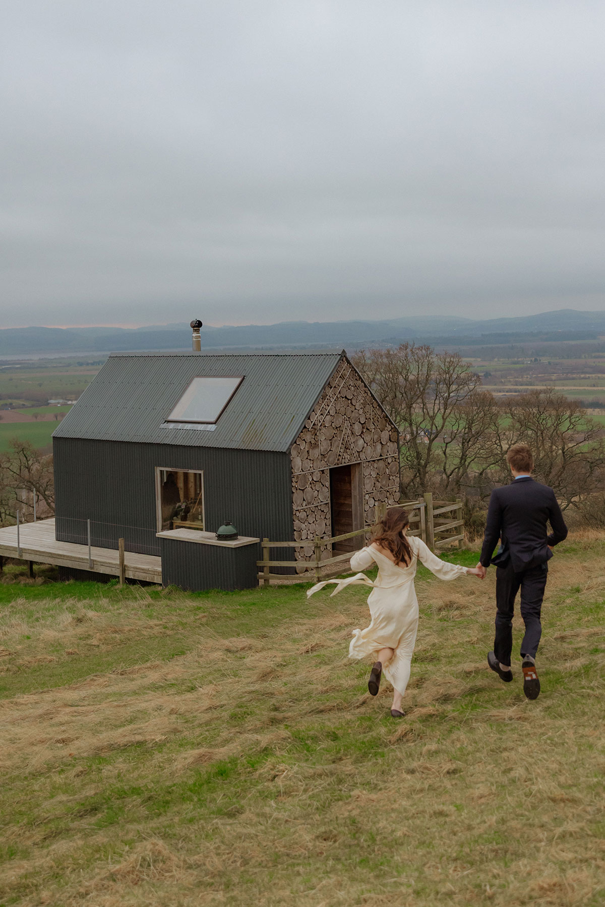 couple running towards timber hut at guardswell farm