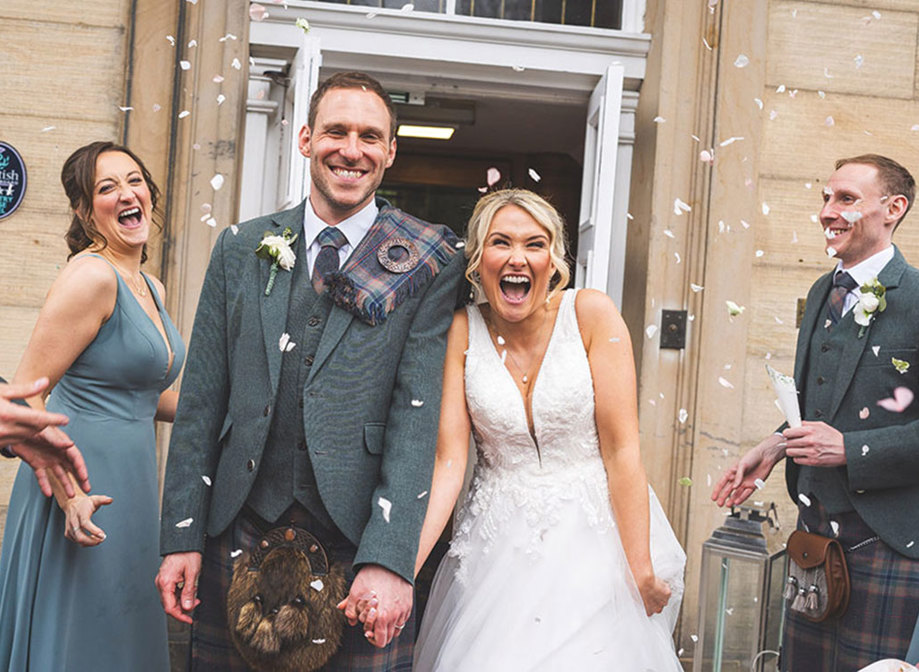 bride and groom hold hands and smile from ear to ear during their confetti toss