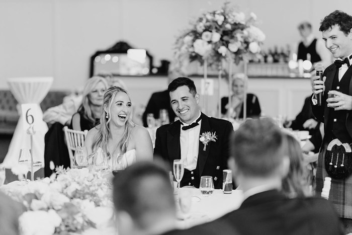 A laughing bride and groom sitting at a table.