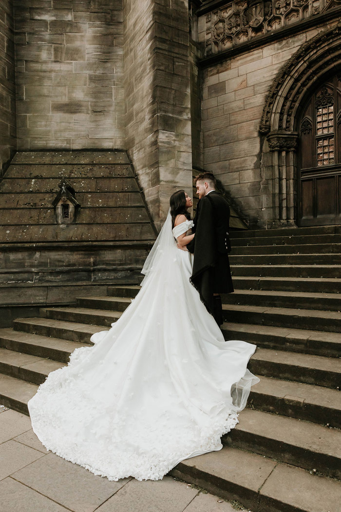 bride with long train standing on steps looking into grooms eyes in edinburgh