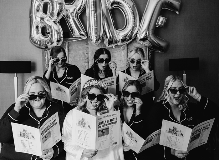 A black and white photo of a group of women holding newspapers and wearing sunglasses