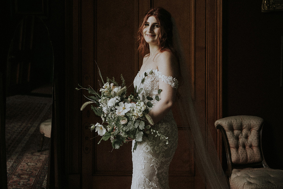 Bride smiling and holding wildflower bouquet with white flowers and green leaves