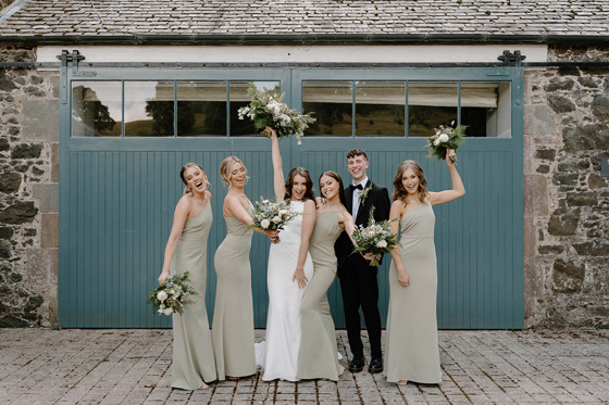 Bride, groom and bridesmaids smiling with their bouquets