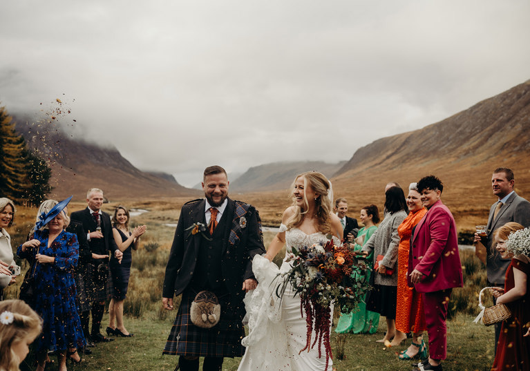 Bride and groom confetti shot in Scottish Highlands with mist-covered hills in background