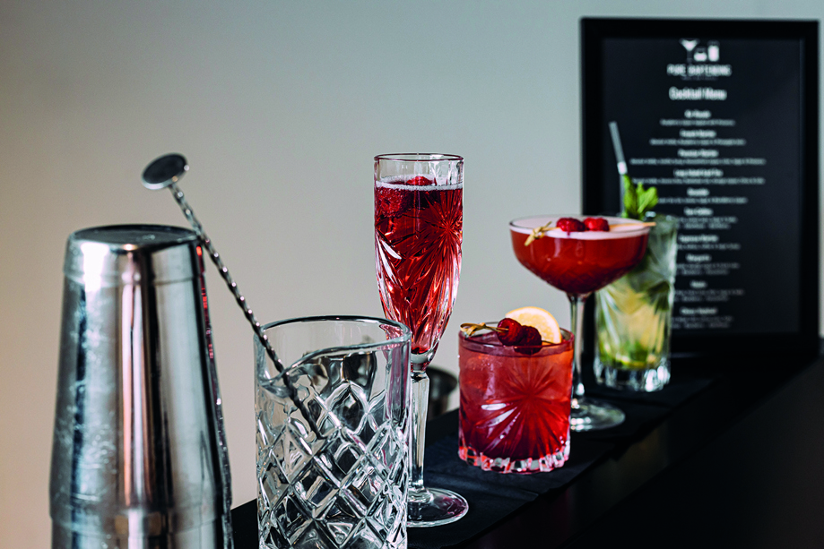 Image of a range of cocktails, cocktail shaker and glass with menu in background