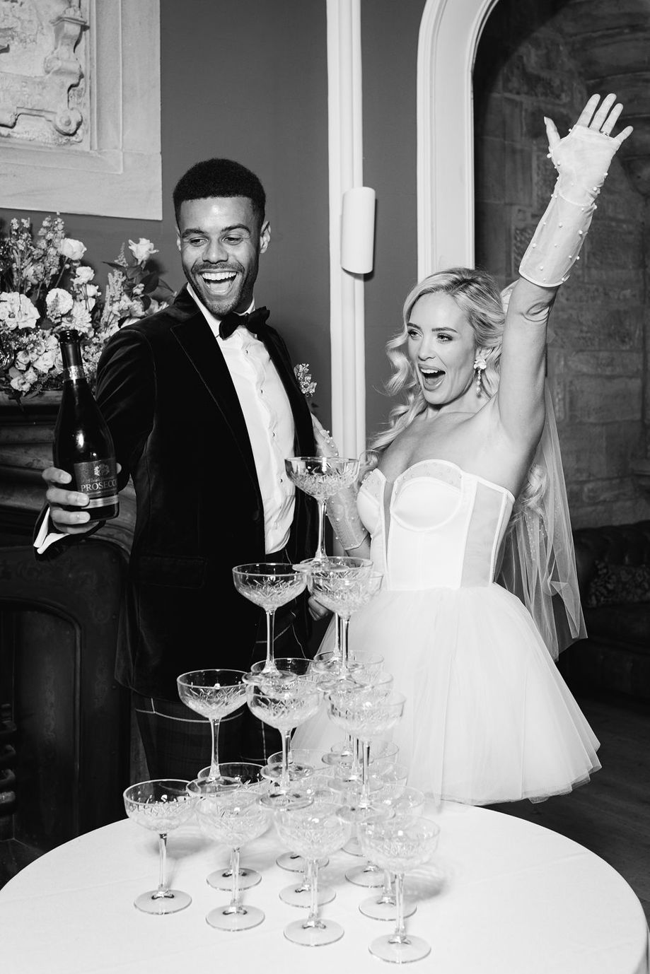 Black and white portrait image of a bride and groom celebrating with Pure Bartending champagne