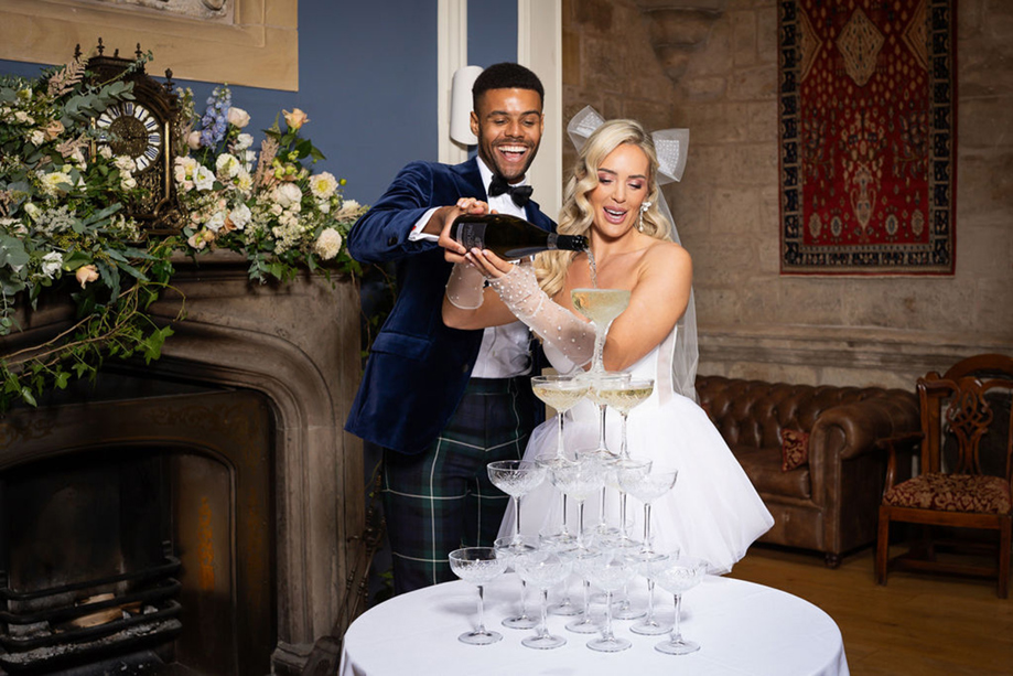 Bride and groom laugh as they pour champagne on champagne tower