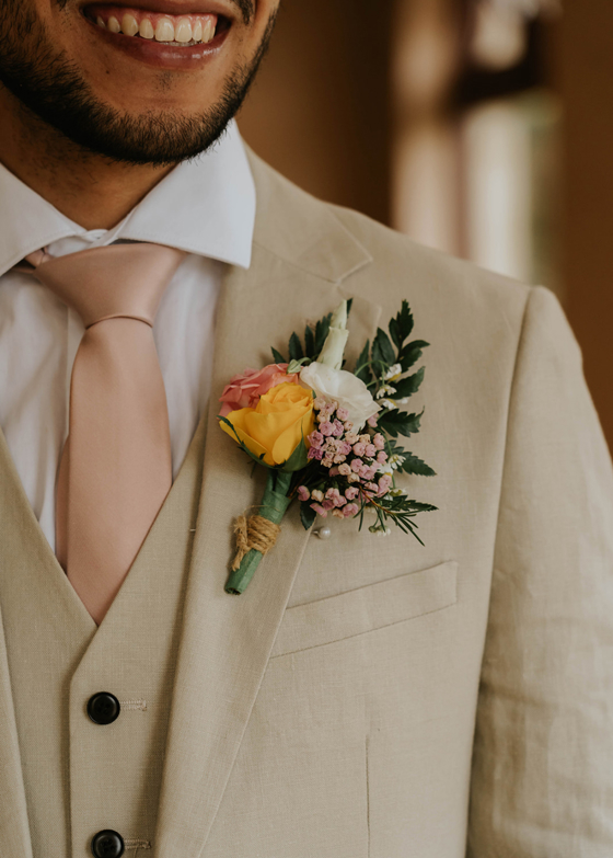 Smiling groom with yellow, pink and white buttonhole 