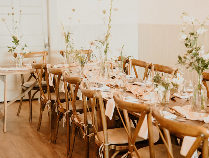 Rustic wedding meal set up with long tables decorated with white flowers in vases