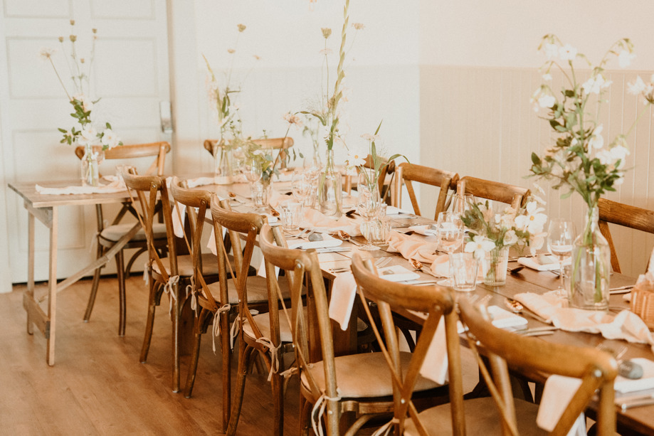 Rustic wedding meal set up with long tables decorated with white flowers in vases