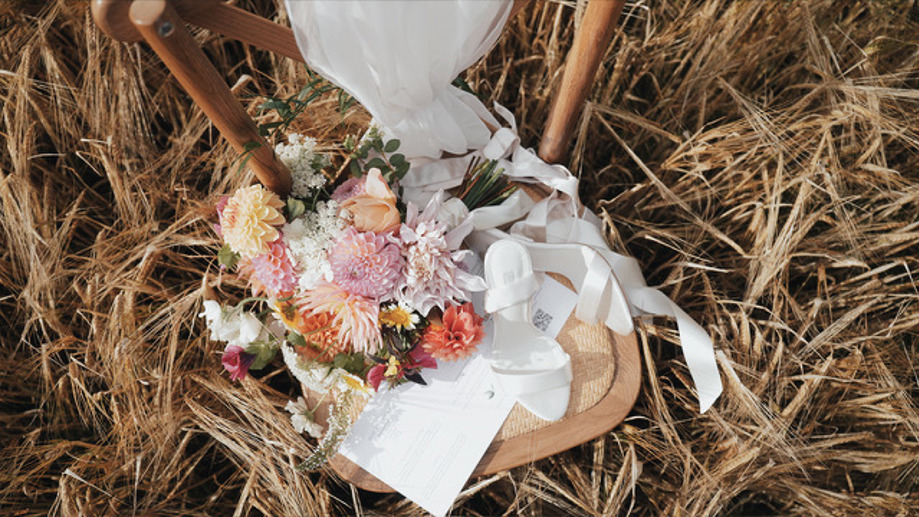 Bouquet and wedding shoes on chair in long grass