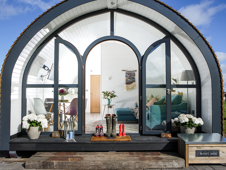 Glamping pod at Maycroft Retreat with bright, modern interiors with three pairs of welly boots outside door.