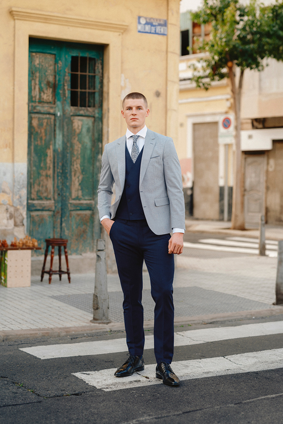 Man in navy and grey three-piece suit with tie on zebra crossing