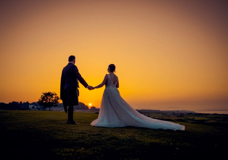 Bride and groom walking during orange sunset