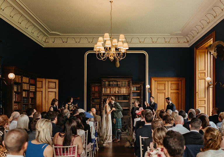 Bride and groom seal the deal with a kiss at the altar in front of clapping guests