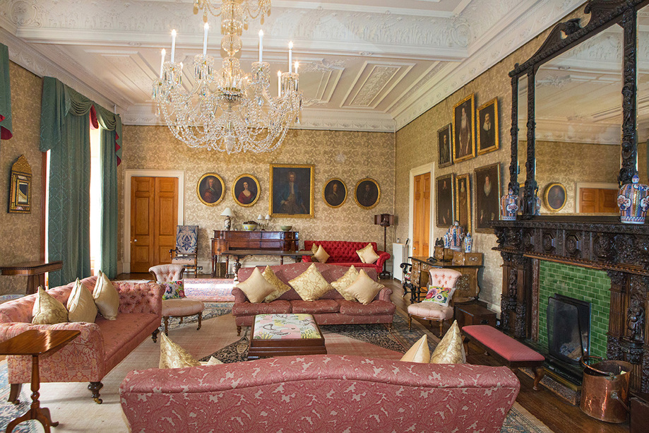 Crystal chandelier hangs above chesterfield sofas in room with regal decor