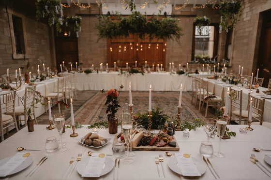 Long tables set out in square format with candlesticks and leafy decor