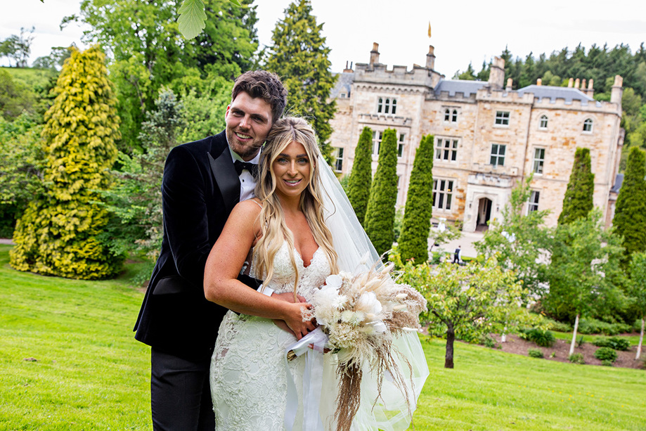 Bride and groom smile on the grounds of Crossbasket Castle