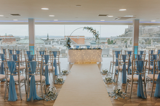 Blue and white decor with foliage covered hoop at altar for wedding ceremony