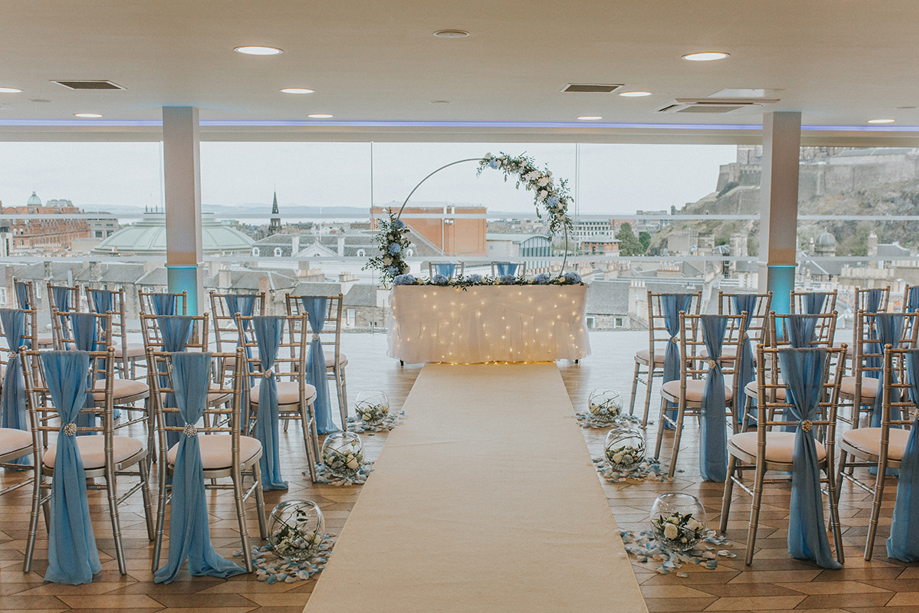 Blue and white decor with foliage covered hoop at altar for wedding ceremony