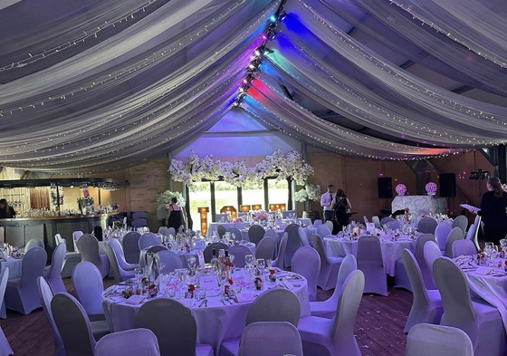 Wedding meal set up with draped rainbow fairy light decorated ceiling