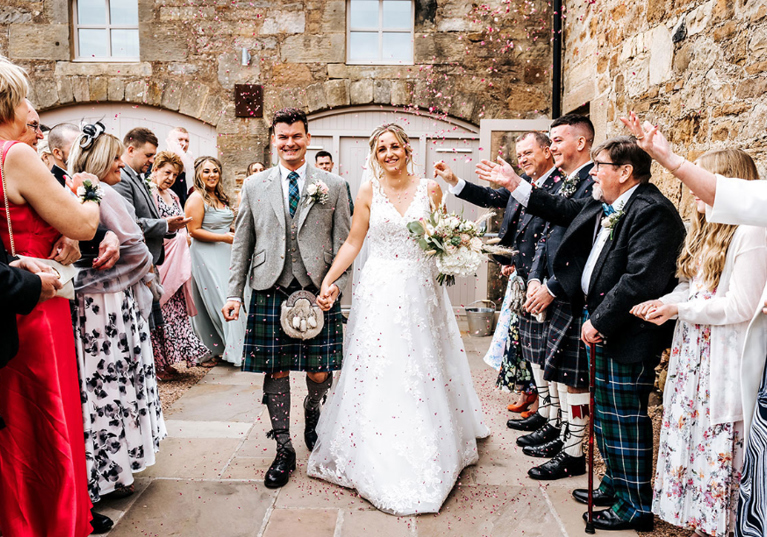 Guests celebrate following wedding ceremony with bride and groom smiling