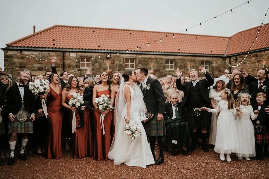 Bride and groom kiss in front of guests in venue Courtyard