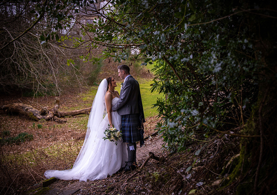 Bride and groom look at each other beside tree on hotel's grounds