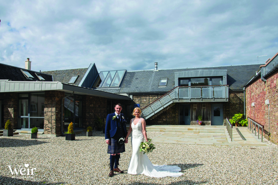 Bride and groom stand outside Ardoch Loch Lomond by Weir Photography