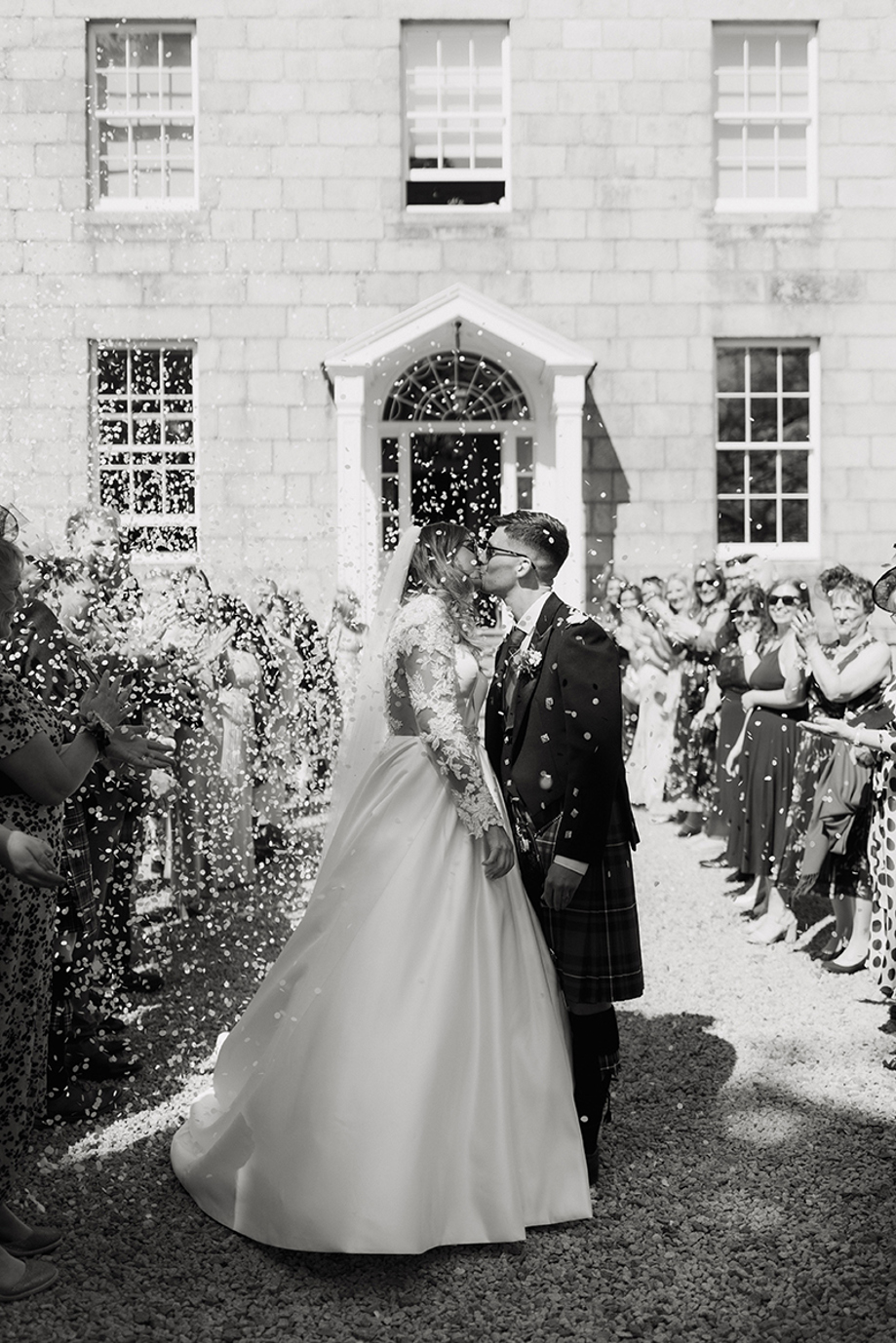 Bride and groom kiss during confetti throw after wedding ceremony at House of Elrick.