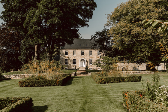 Exterior of country house wedding venue, House of Elrick, on Elrick Estate in Aberdeenshire. Blue skies in background and lush manicured gardens in foreground.