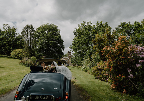 Bride and groom driving away in wedding car