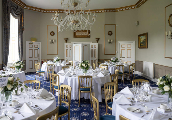 Dining set up with gold chairs and cream roses on tables