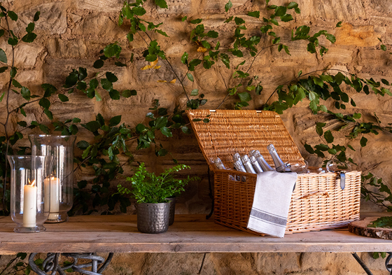 Picnic basket with bottles inside on table with candles