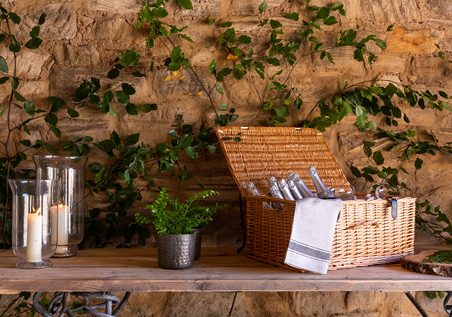 Picnic basket with bottles inside on table with candles