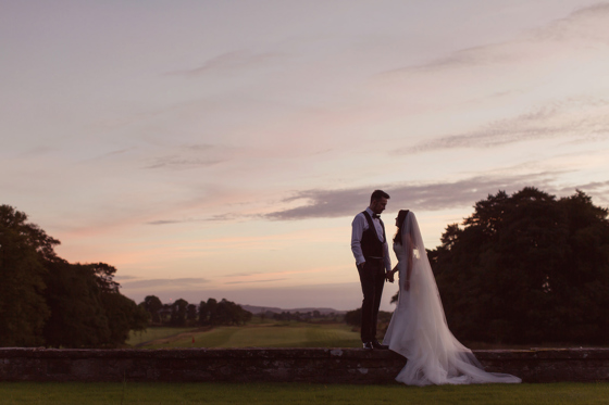 Side view of a bride and groom on the grounds of Rowallan Castle at sunset.