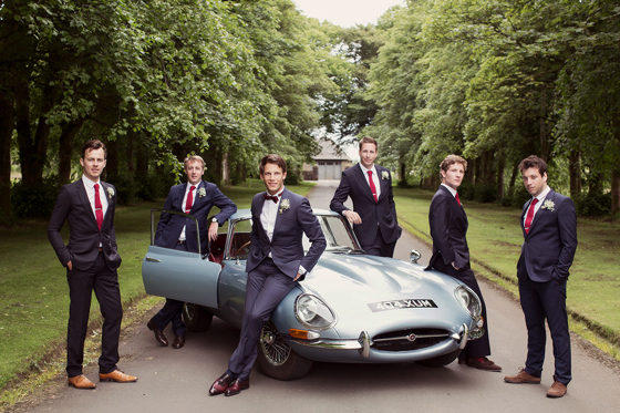 Groomsmen pose next to sports car at Rowallan Castle.