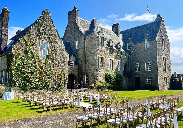 Side view of Rowallan Castle with outdoor wedding set up on a sunny day.