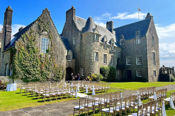 Side view of Rowallan Castle with outdoor wedding set up on a sunny day.