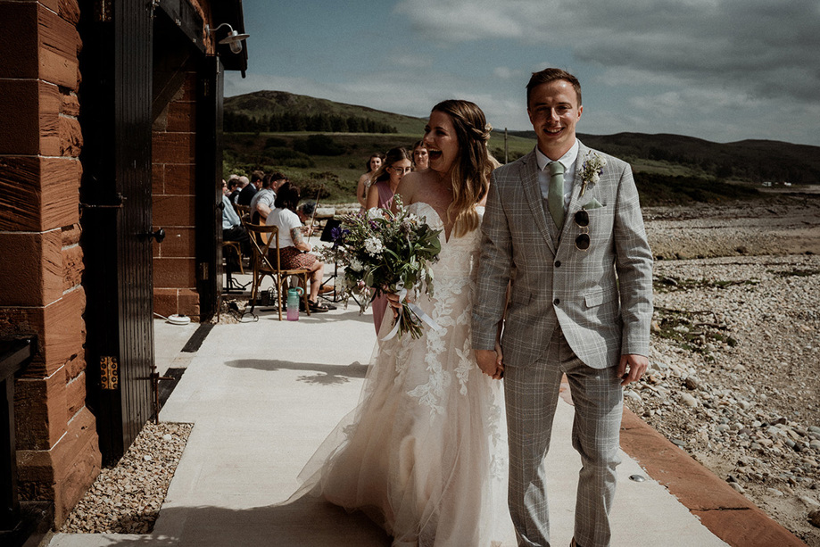 Bride and groom laugh as they walk out of their ceremony