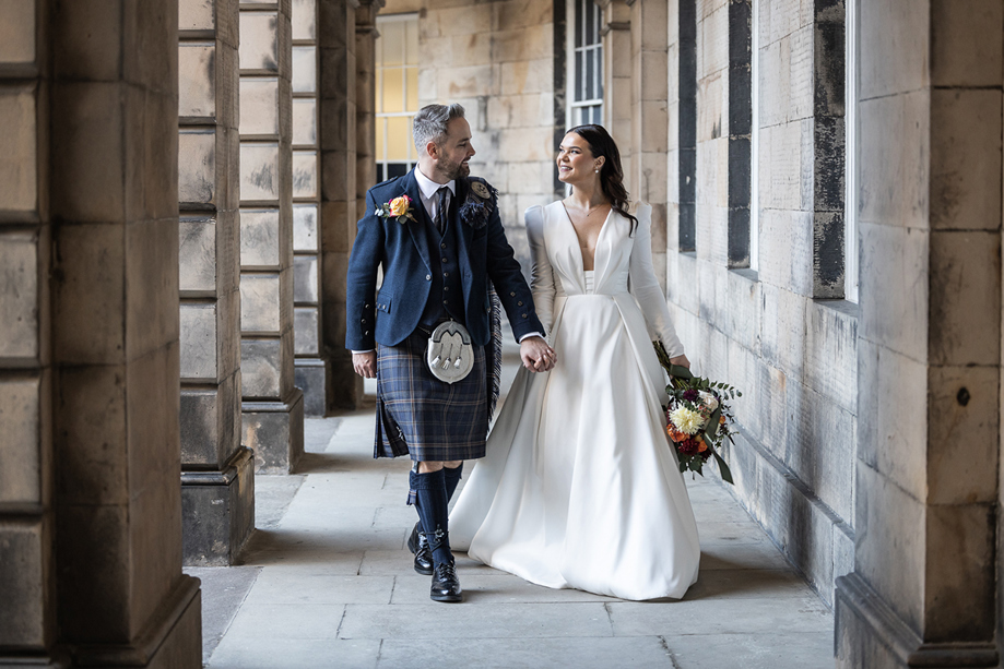 Bride and groom outside The Signet Library holding hand and smiling at one another